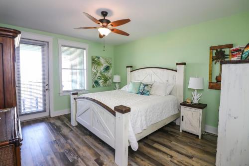 - une chambre avec un lit blanc et un ventilateur de plafond dans l'établissement Stunning Sunsets Steps from Pool Lazy River Ocean Bay Views, à Galveston
