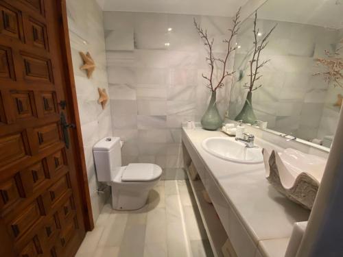 a white bathroom with a toilet and a sink at Villa Playa Mojacar in Mojácar