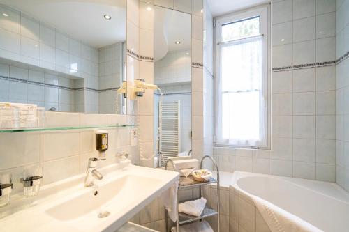 a white bathroom with a tub and a sink at Familienhotel Post in Millstatt