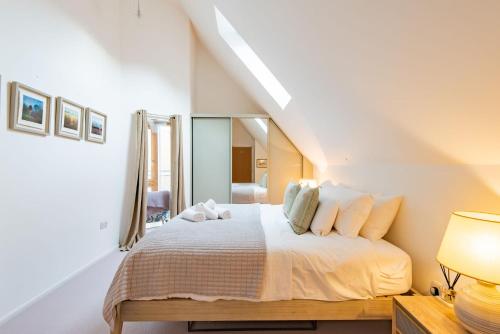 a white bedroom with a bed with a mirror at The Loft at Emperor Court by Bloom Stays in Canterbury