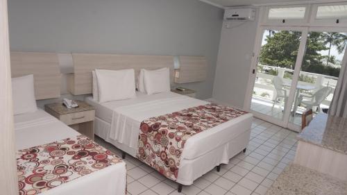 a hotel room with two beds and a balcony at Sueds Plaza in Porto Seguro
