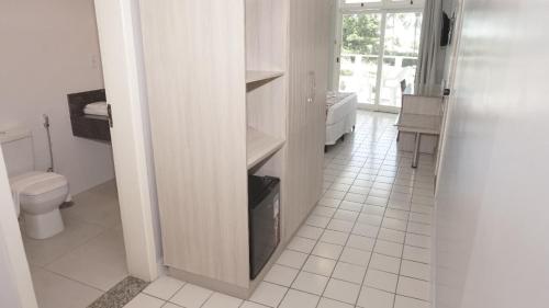 a white bathroom with a toilet and a sink at Sueds Plaza in Porto Seguro