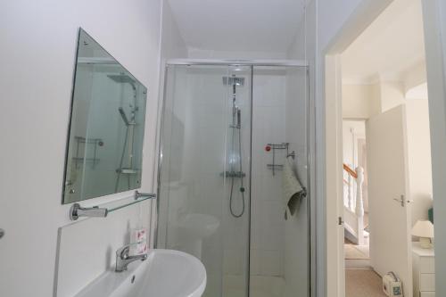 a white bathroom with a shower and a sink at Bella vista in Chichester