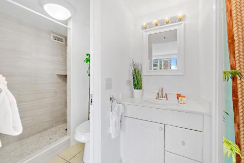 a white bathroom with a sink and a mirror at Beautiful Studio in the Heart of Vibrant Waikiki in Honolulu