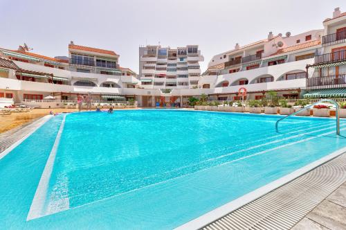 a large swimming pool in front of some buildings at Modern apartment in Parque Royal I, Playa Fañabe in Adeje