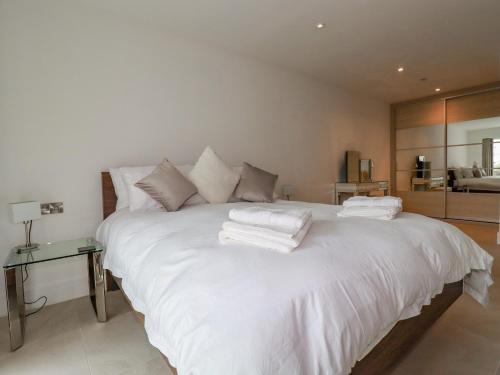 a large white bed with white towels on it at 13 Cliff Edge in Newquay