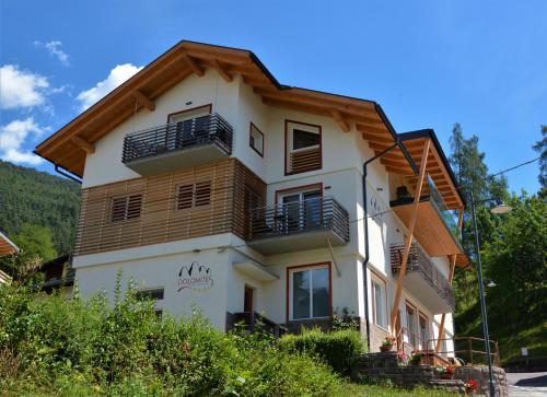 a white house with a wooden roof at DOLOMITES B&B - Suites, Apartments and SPA in Tesero