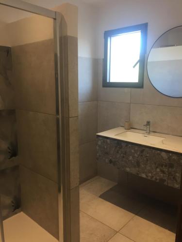 une salle de bain avec un lavabo et un miroir dans l'établissement Maison neuve avec piscine et terrasse extérieur, à Corbara