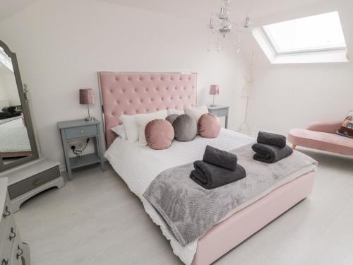 a bedroom with a pink bed with pillows and a mirror at Horseshoe Cottage in Coldstream