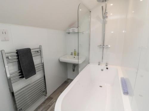 a white bathroom with a tub and a sink at Horseshoe Cottage in Coldstream