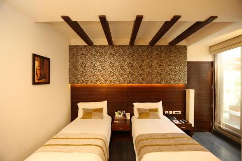 een kamer met twee bedden en een tafel erin bij Hotel Icon in Chandīgarh