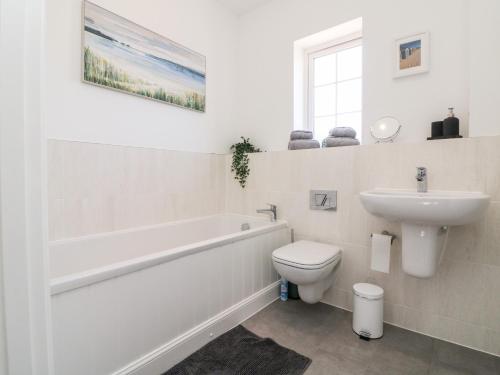 a bathroom with a tub and a toilet and a sink at 1 Marsh Gardens in Dunster