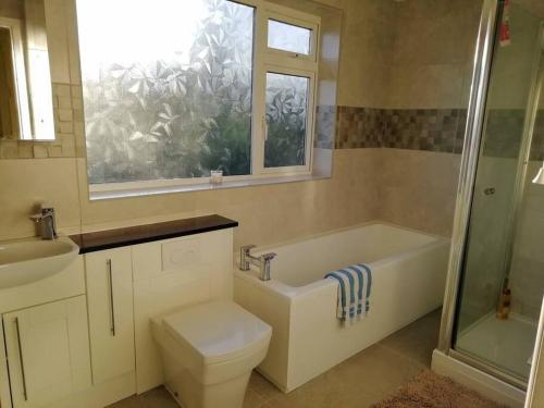 a bathroom with a tub and a toilet and a window at Country Home with Gardens in Newtown
