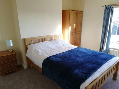 a bedroom with a bed with a blue blanket on it at Country Home with Gardens in Newtown