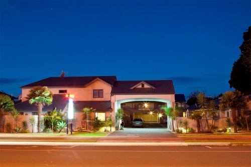 a house with a car parked under a garage at night at Aquarius Motor Inn in Mount Maunganui