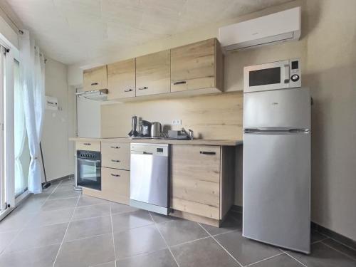 een keuken met een witte koelkast en houten kasten bij Charmant logement avec piscine in Le Cannet-des-Maures