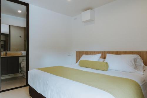 a bedroom with a large white bed with a mirror at Travelers Rio Verde Living Suites in Rionegro