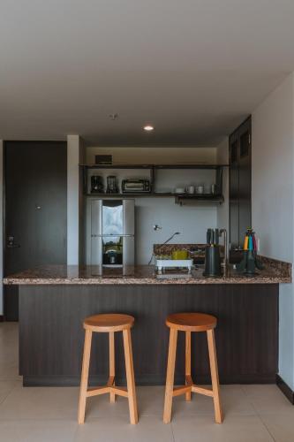 a kitchen with two wooden stools at a counter at Travelers Rio Verde Living Suites in Rionegro
