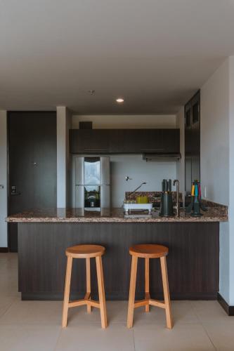 a kitchen with two wooden stools in front of a counter at Travelers Rio Verde Living Suites in Rionegro