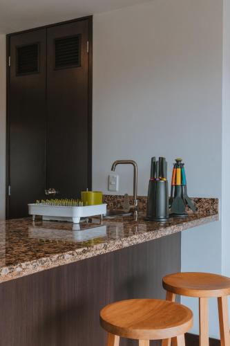 a kitchen with two stools and a counter top at Travelers Rio Verde Living Suites in Rionegro