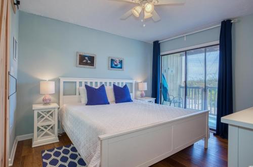 a bedroom with a bed with blue pillows and a window at BEAUTIFUL BEACHFRONT-Oceanfront First Floor 2BR 2BA Condo in Cherry Grove, North Myrtle Beach! RENOVATED with a Fully Equipped Kitchen, 3 Separate Beds, Pool, Private Patio & Steps to the Sand! in Myrtle Beach