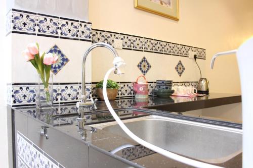 a kitchen sink with a faucet and flowers on a counter at The Egerton - Walk to Jonker - Ensuite - Heritage in Melaka
