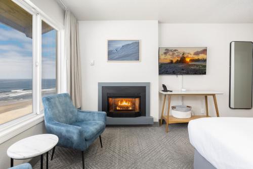 a living room with a fireplace and a blue chair at Surfland Hotel in Lincoln City