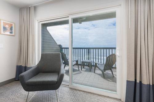 a room with a chair and a balcony with a view at Surfland Hotel in Lincoln City
