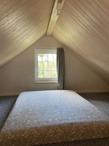a bedroom with a bed in a attic with a window at Mandarinas in Anykščiai