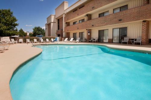 a large blue swimming pool in front of a building at Clarion Pointe OKC Airport in Oklahoma City