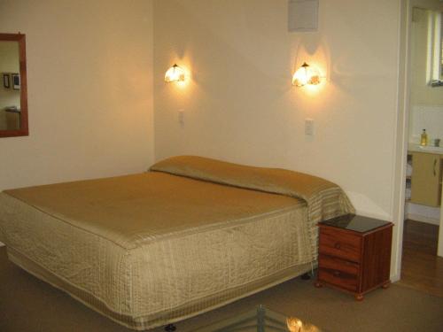 a bedroom with two beds and two lights on the wall at Shortland Court Motel in Thames