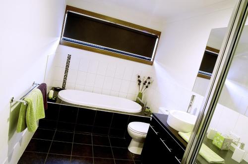 a bathroom with a tub and a toilet and a sink at Abode Bendigo Apartments in Bendigo