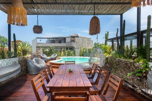 een patio met een houten tafel en stoelen en een zwembad bij Unique 6BR townhouse,12ppl, Private rooftop pool in Tulum