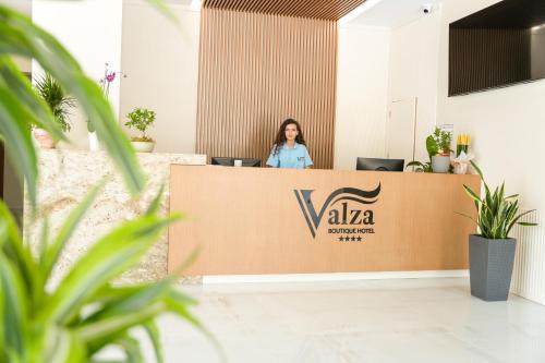 a woman standing behind a reception desk in a lobby at Valza Boutique Hotel in Vlorë