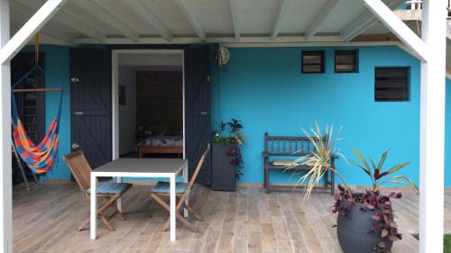 a patio with a table and a blue wall at Kaz kad in Sainte-Rose
