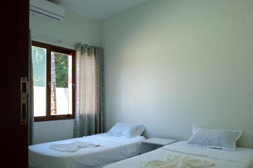 two beds in a room with a window at Bilene Brown House in Vila Praia Do Bilene