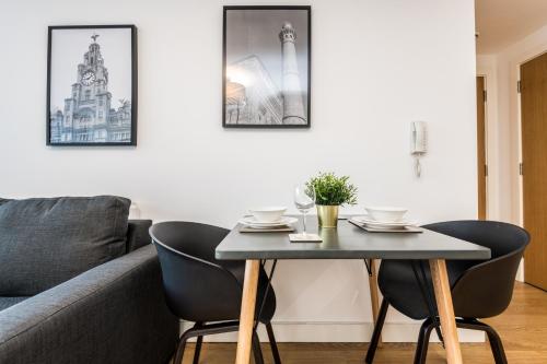 a table and chairs in a living room with a couch at Host & Stay - The Pall Mall Balcony Apt in Liverpool