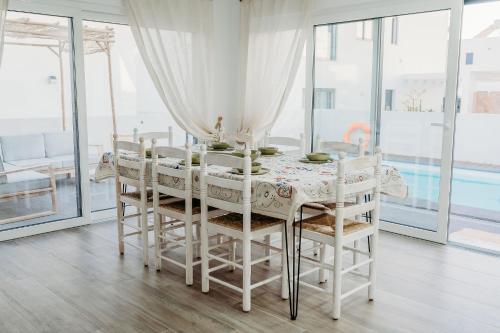 uma sala de jantar branca com uma mesa e cadeiras em Villa Saudade - Sustainable Living em Porto Covo