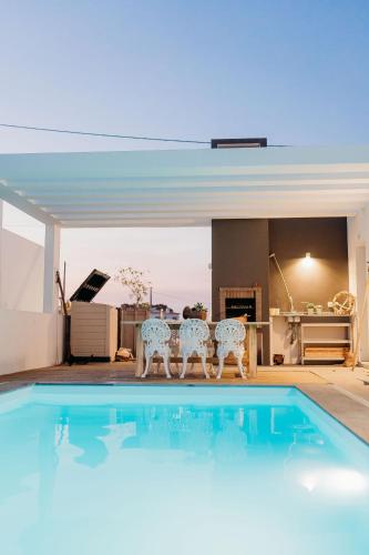 a swimming pool with two chairs and a table at Villa Saudade - Sustainable Living in Porto Covo