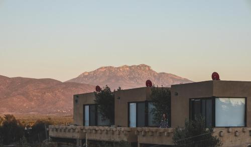 a person standing in front of a house with mountains in the background at Estancias Sierravita in Valle de Guadalupe