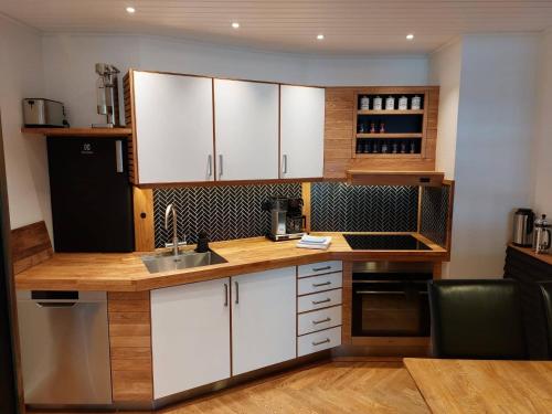 a kitchen with white cabinets and a wooden counter top at Tórshavn City Apartment in Tórshavn