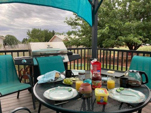 a table with plates of food and a grill on a deck at Kokopelli Kottage in Kanab