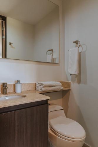 a bathroom with a toilet and a sink and a mirror at Travelers Rio Verde Living Suites in Rionegro
