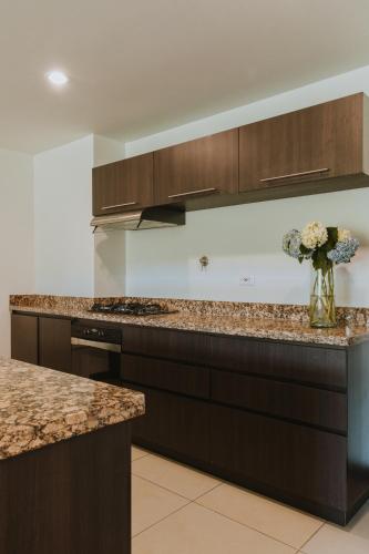 a kitchen with brown cabinets and a vase of flowers at Travelers Rio Verde Living Suites in Rionegro