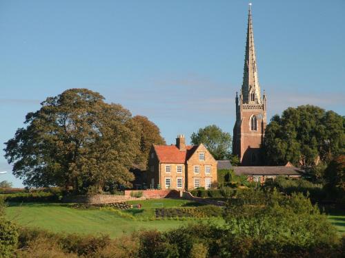 a church with a steeple in the distance with a green yard at Braunston Manor Cottage in Braunston