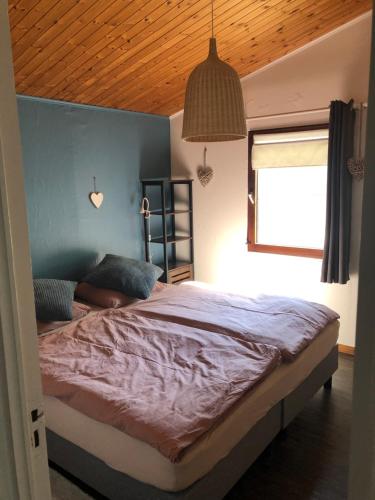 1 dormitorio con 1 cama grande y techo de madera en Chalet Happiness en Zutendaal