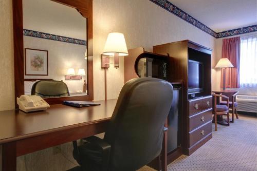 a hotel room with a desk with a telephone and a mirror at Americas Best Value Inn and Suites Saint Charles in St. Charles