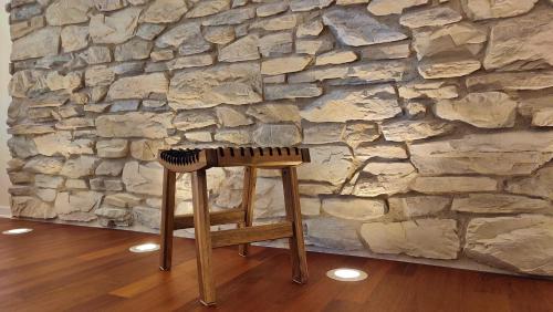 un tabouret en bois devant un mur en pierre dans l'établissement dalTURRI - Casa vacanze al mare - Relax e PRIVATE WELLNESS con sauna, à Duino