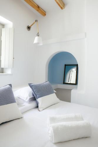 a white bedroom with a white bed with blue pillows at Agapi Home in Agápi
