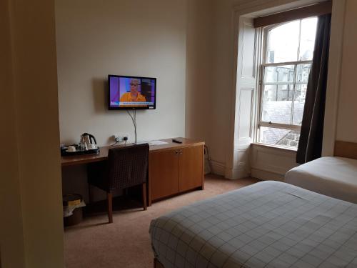 a hotel room with a desk and a bed and a television at Aberdeen House in Aberdeen